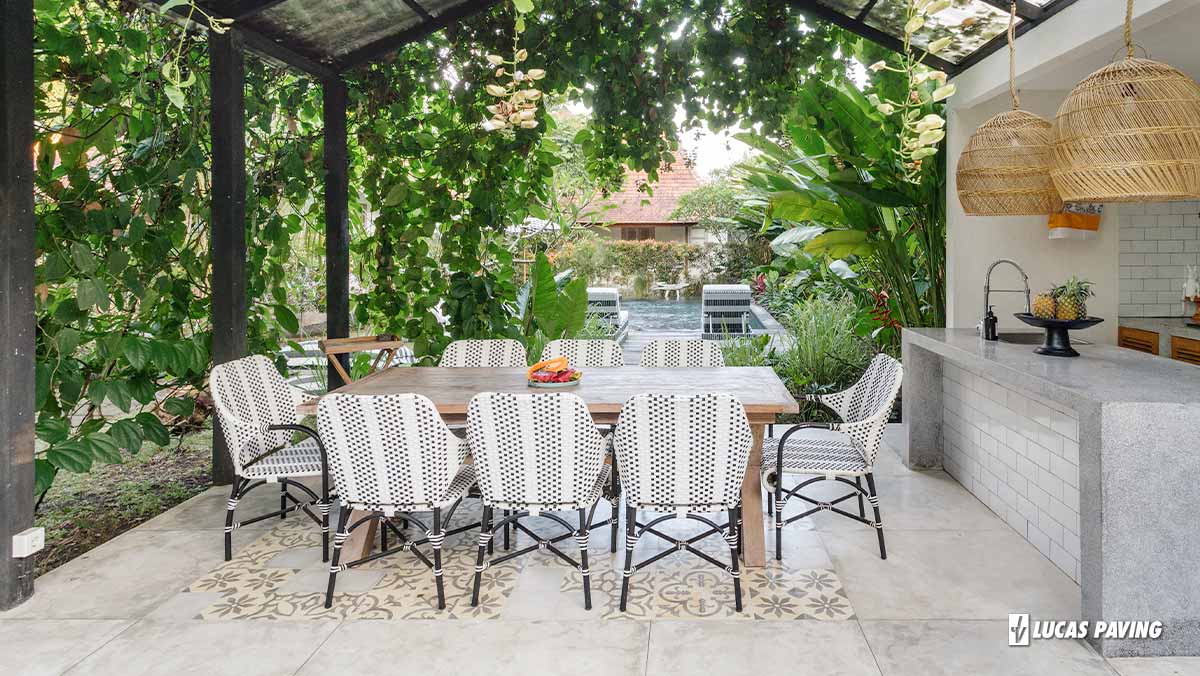 A stylish patio featuring an outdoor kitchen, dining set, and tile flooring.